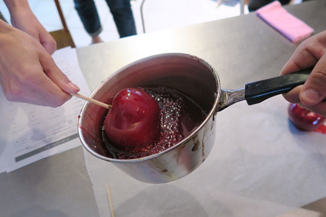 150℃以上に沸かした飴に串刺しのりんごをくぐらす